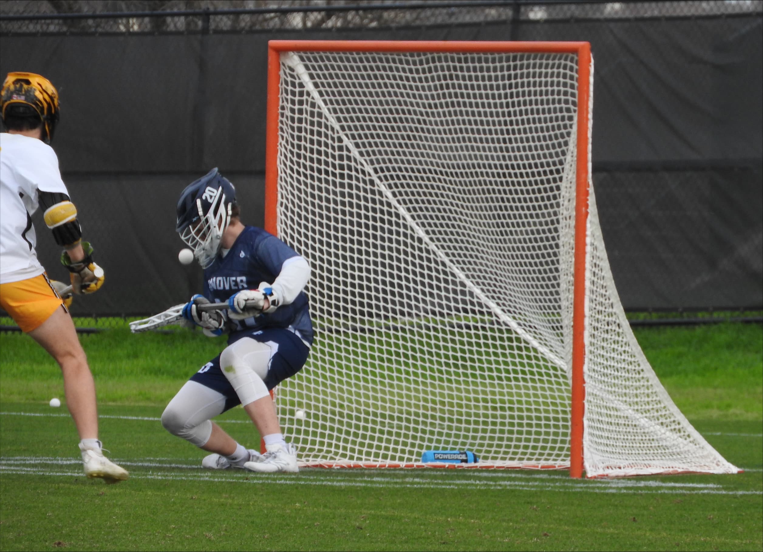 Lacrosse goalie tracking the ball during a save near the goal